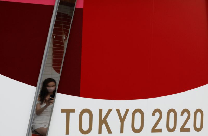 &copy; Reuters. A woman wearing a protective mask, following the coronavirus disease (COVID-19) outbreak, is reflected on a metal bar on an advertisement for Tokyo 2020 Olympic Games in Tokyo, Japan, July 7, 2021.   REUTERS/Kim Kyung-Hoon/