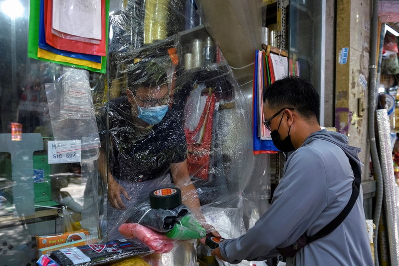 &copy; Reuters. FILE PHOTO: A man buys goods at a shop covered with plastic amid the coronavirus (COVID-19) pandemic, in Hanoi, Vietnam, May 31. REUTERS/Thanh Hue