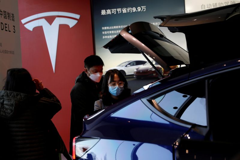 © Reuters. FILE PHOTO: Visitors wearing face masks check a China-made Tesla Model Y sport utility vehicle (SUV) at the electric vehicle maker's showroom in Beijing, China January 5, 2021. REUTERS/Tingshu Wang