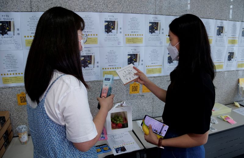 &copy; Reuters. Women take a look at items at a faeces currency market at Ulsan National Institute of Science and Technology (UNIST) in Ulsan, South Korea, July 6, 2021. Picture taken on July 6, 2021. REUTERS/Daewoung Kim