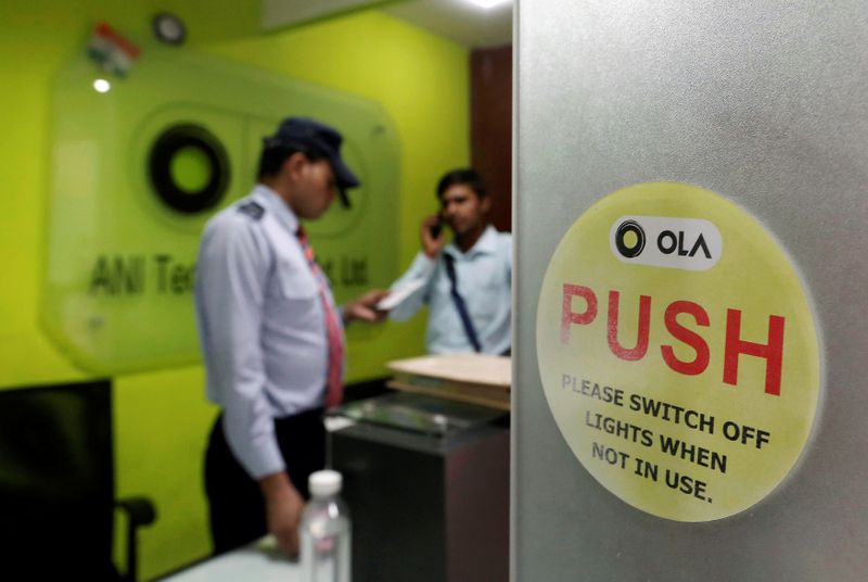 &copy; Reuters. An employee speaks over his phone as a private security guard looks on at the front desk inside the office of Ola cab service in Gurugram, previously known as Gurgaon, on the outskirts of New Delhi, India, April 20, 2016. REUTERS/Anindito Mukherjee/Files