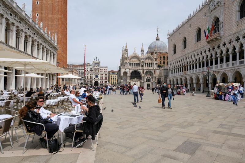 &copy; Reuters. FILE PHOTO: People sit at outdoor tables at St. Mark's Square as Italy lifts quarantine restrictions for travellers arriving from European Union countries, Britain and Israel and begins offering COVID-free flights in a bid to revive the tourism industry, 