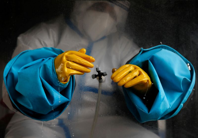 © Reuters. FILE PHOTO: A health worker wearing personal protective equipment (PPE) sanitizes his gloves before taking a polymerase chain reaction (PCR) test from a mobile swab collection vehicle, amid the major second wave of the coronavirus disease (COVID-19) in Kathmandu, Nepal May 19, 2021. REUTERS/Navesh Chitrakar     