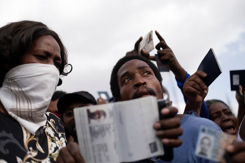 © Reuters. مواطنون من هايتي يحلمون جوازات سفرهم عند السفارة الأمريكية في بورت أو برنس يوم 9 يوليو تموز 2021 - رويترز  