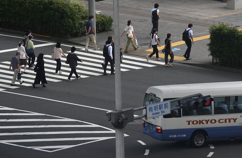 © Reuters. Workers cross a road during the morning rush hour, ahead of the Tokyo 2020 Olympic Games that have been postponed to 2021 due to the coronavirus disease (COVID-19) pandemic, in Tokyo, Japan, July 15, 2021. REUTERS/Toby Melville
