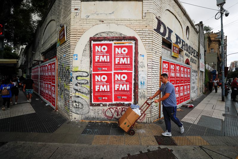 &copy; Reuters. A man walks past posters while demonstrators protest outside the National Congress, as members of the parliament debate the government's agreement with the International Monetary Fund (IMF), in Buenos Aires, Argentina March 10, 2022. REUTERS/Agustin Marca