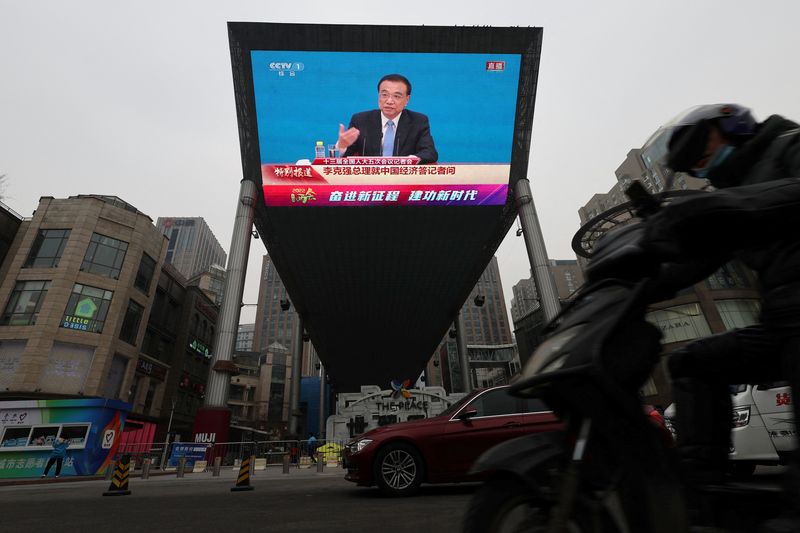 &copy; Reuters. A rider drives past a giant screen showing a news conference by Chinese Premier Li Keqiang, following the closing session of the National People's Congress (NPC) at the Great Hall of the People in Beijing, China March 11, 2022. REUTERS/Tingshu Wang
