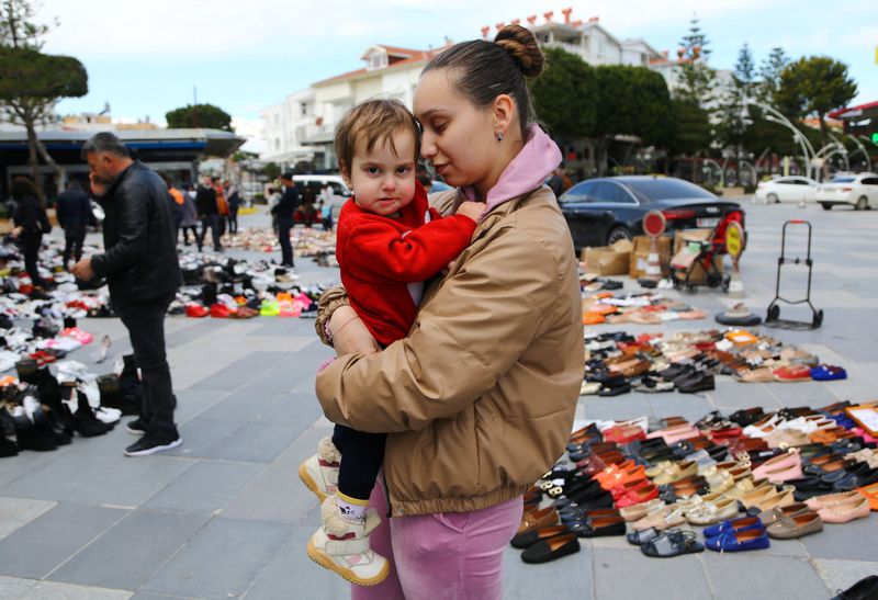 © Reuters. أوكرانية فرت من القصف الروسي تحمل طفلتها في أنطاليا بتركيا في التاسع من مارس آذار 2022. تصوير كان سويتورك- رويترز.