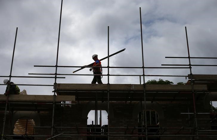 © Reuters. A builder assembles scaffolding as he works on new homes, in south London June 3, 2014.   REUTERS/Andrew Winning/Files