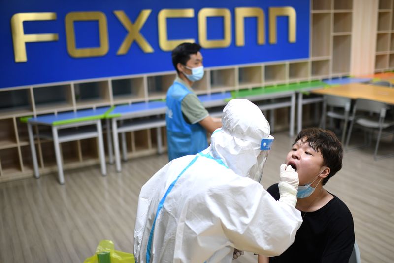 &copy; Reuters. A medical worker in a protective suit collects a swab from a worker for nucleic acid testing at a Foxconn factory, following new cases of the coronavirus disease (COVID-19) in Wuhan, Hubei province, China August 5, 2021. Picture taken August 5, 2021. Chin