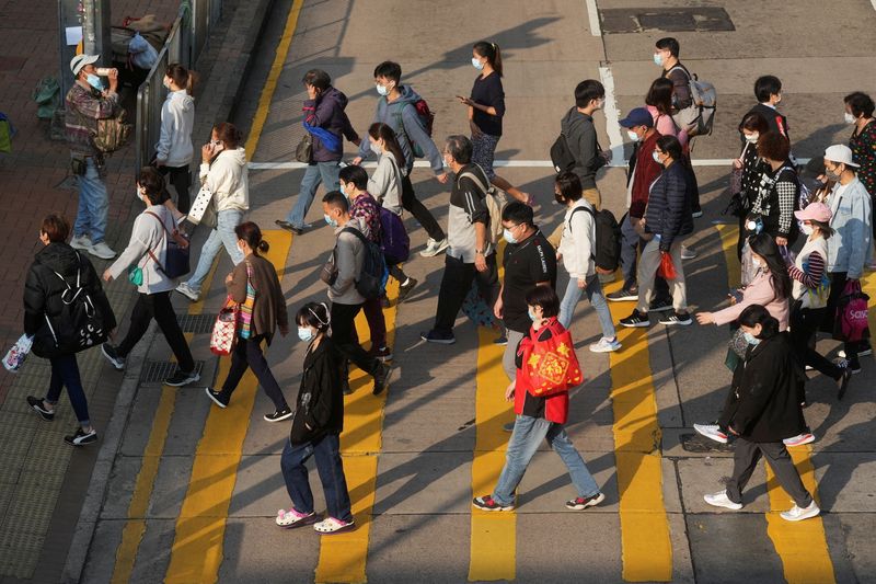 &copy; Reuters. FILE PHOTO: People wearing face masks cross a street following the coronavirus disease (COVID-19) outbreak, in Hong Kong, China February 15, 2022. REUTERS/Lam Yik