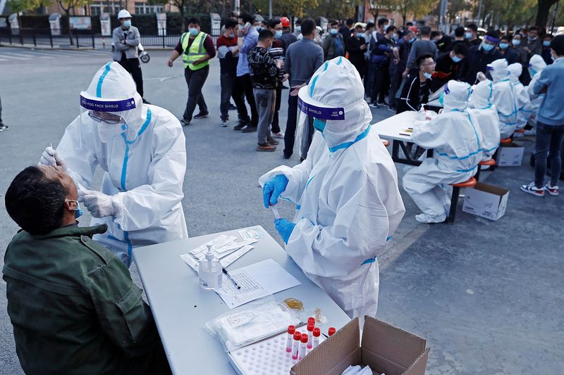 &copy; Reuters. A medical worker in protective suit collects a swab from a resident at a makeshift nucleic acid testing site, following cases of the coronavirus disease (COVID-19) in Shanghai, China March 11, 2022. Picture taken March 11, 2022. cnsphoto via REUTERS   