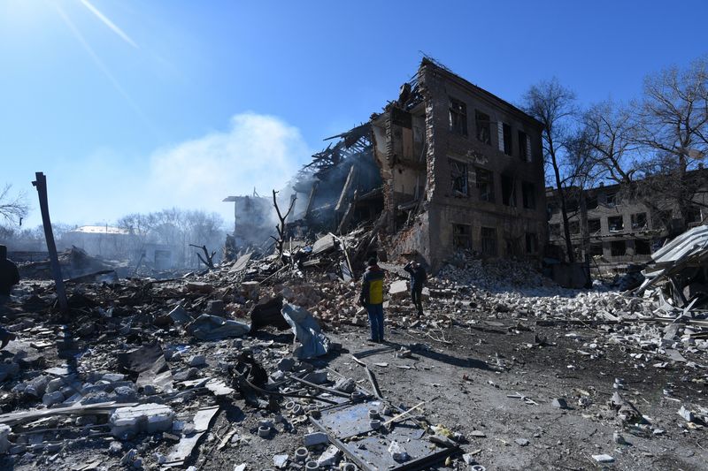 &copy; Reuters. FOTO DE ARCHIVO: Personas frente a una fábrica de zapatos destruida tras un ataque con misiles, en medio de la invasión rusa, en Dnipro, Ucrania, el 12 de marzo,  2022. REUTERS/Mykola Synelnikov