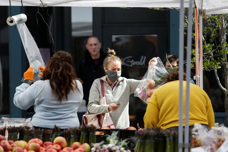 &copy; Reuters. FILE PHOTO: A customer pays for produce at the Ballard Farmers' Market which reopened Sunday with new safety measures, including encouraging people to use a credit or debit card instead of cash, as efforts continue to help slow the spread of the coronavir