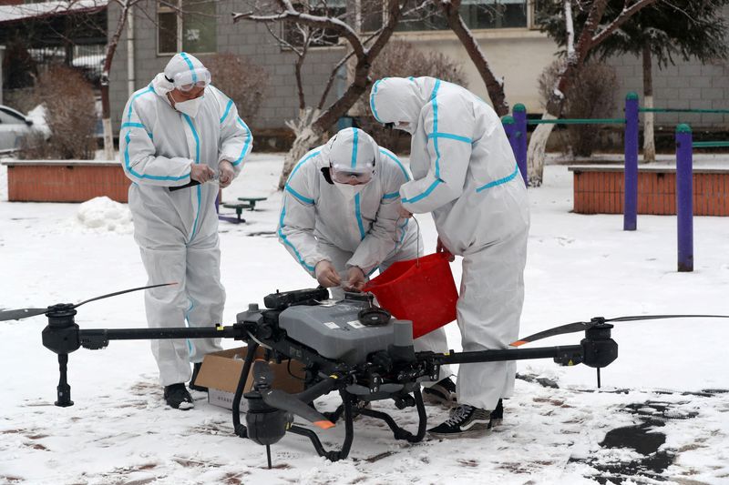 &copy; Reuters. Trabajadores con trajes de protección preparan un dron sobre la nieve para desinfectar un complejo residencial bajo confinamiento, tras el brote de la enfermedad del coronavirus (COVID-19) en Changchun, provincia de Jilin, China, 14 de marzo de 2022. REU