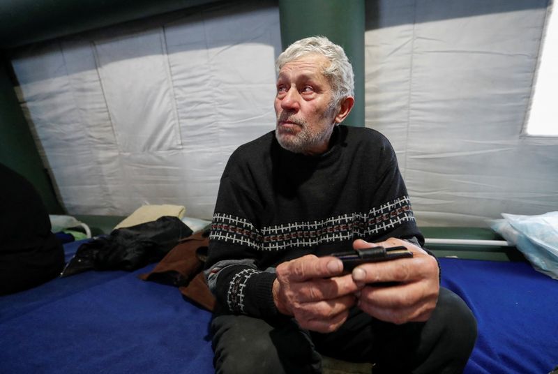 © Reuters. رجل يجلس في مخيم للاجئين مع من تم إجلاؤهم من منطقة ماريوبول في مستوطنة بيزيمينوي خلال الصراع الأوكراني الروسي في منطقة دونيتسك يوم الثامن من مارس آذار 2022. تصوير: الكسندر إرموشينكو - رويترز.