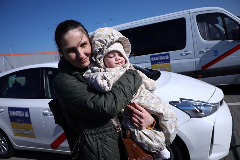 &copy; Reuters. Una mujer ucraniana llamada Olga, de 38 años, sostiene a su hija Vera, de 6 meses, cerca de los taxis españoles, frente al centro de recepción de refugiados, tras la invasión rusa de Ucrania,en Nadarzyn, Polonia, el 14 de marzo de 2022. Foto tomada el