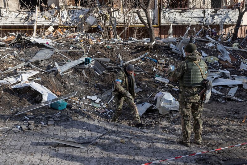 © Reuters. Soldados ucranianos inspeccionan el área en frente de un edificio de departamentos golpeado por la invasión de Rusia a Ucrania en Kiev, 15 de marzo del  2022. REUTERS/Marko Djurica