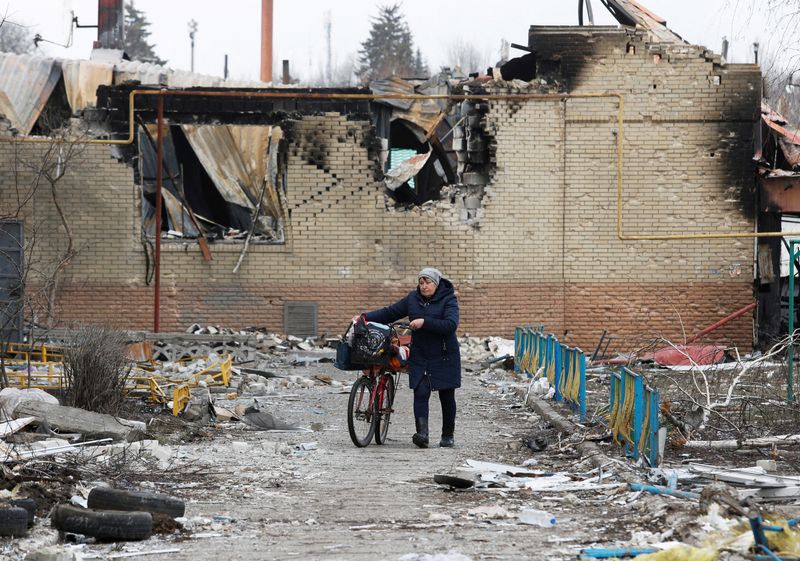 &copy; Reuters. FILE PHOTO: A woman walks with a bicycle next to a building damaged during Ukraine-Russia conflict in the separatist-controlled town of Volnovakha in the Donetsk region, Ukraine March 15, 2022. REUTERS/Alexander Ermochenko    