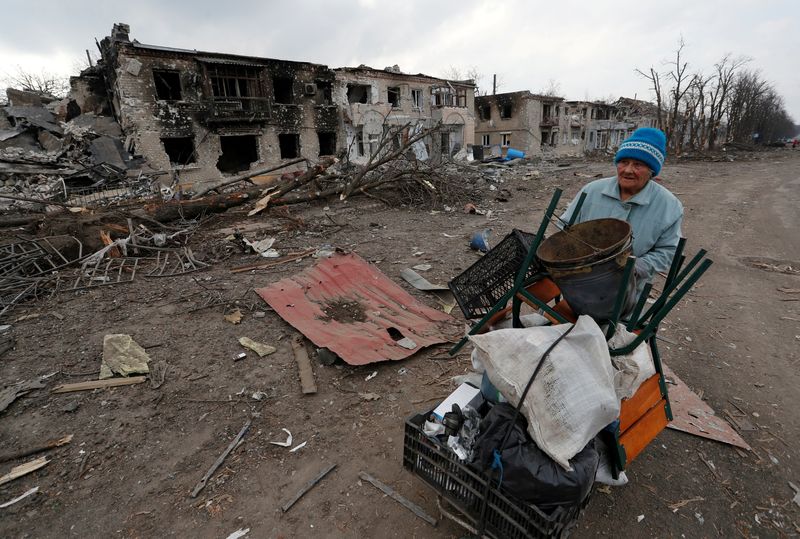 © Reuters. FILE PHOTO: A woman pushes a trolley with her belongings along a street damaged during Ukraine-Russia conflict in the separatist-controlled town of Volnovakha in the Donetsk region, Ukraine March 15, 2022. REUTERS/Alexander Ermochenko/File Photo