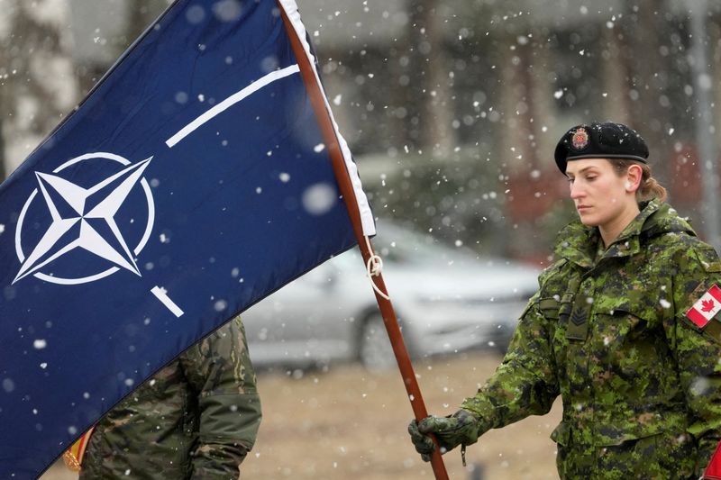 &copy; Reuters. FOTO DE ARCHIVO: Una soldado canadiense sostiene una bandera con el emblema de la OTAN en Adazi, Letonia, el 8 de marzo de 2022. REUTERS/Ints Kalnins