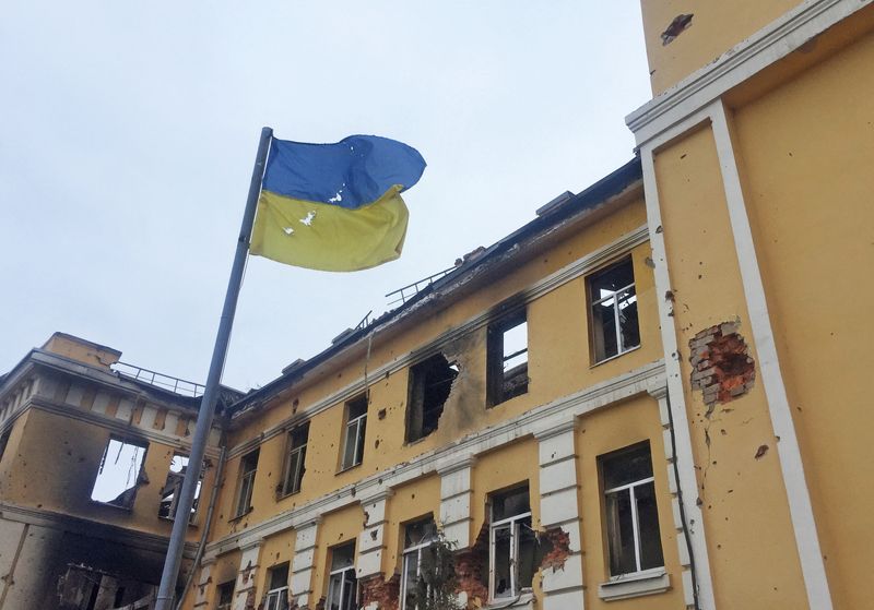&copy; Reuters. FILE PHOTO: The Ukrainian national flag is seen in front of a school which, according to local residents, was on fire after shelling, as Russia's invasion of Ukraine continues, in Kharkiv, Ukraine February 28, 2022. REUTERS/Vitaliy Gnidyi/File Photo