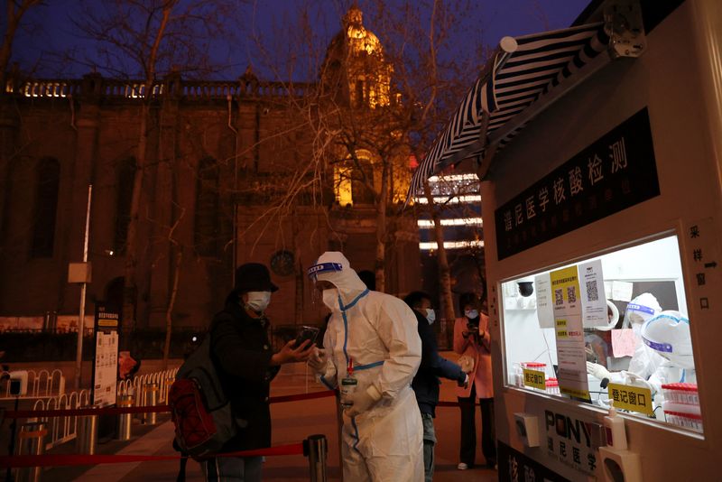 &copy; Reuters. Un trabajador con un traje de protección ayuda a una persona a registrarse para las pruebas de ácido nucleico en un punto móvil cerca de una iglesia católica, tras el brote de la enfermedad del coronavirus (COVID-19), en Pekín, China, 16 de marzo de 