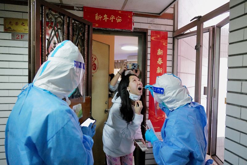 &copy; Reuters. Un trabajador con traje de protección recoge un hisopo de una residente en un complejo residencial bajo confinamiento, tras el brote de la enfermedad por coronavirus (COVID-19) en Shenzhen, provincia de Guangdong, China, 14 de marzo de 2022. REUTERS/cnsp