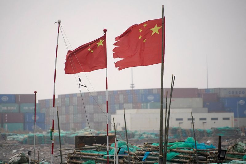 &copy; Reuters. FOTO DE ARCHIVO: Banderas chinas ondean cerca de contenedores apilados en el puerto de aguas profundas de Yangshan en Shanghái, China 13 de enero de 2022.  REUTERS/Aly Song/