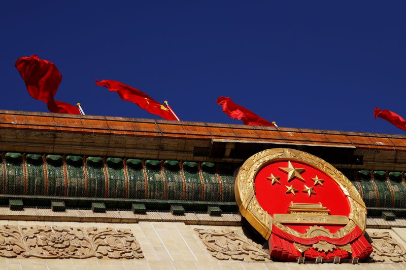 &copy; Reuters. FILE PHOTO: A Chinese flag flutters above the national emblem on the Great Hall of the People before the opening session of the National People's Congress (NPC) in Beijing, China March 5, 2022. REUTERS/Carlos Garcia Rawlins