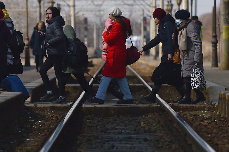 &copy; Reuters. لاجئون يعبرون القضبان لركوب قطار متجه إلى بوخارست في رومانيا يوم الخميس. تصوير رويترز.