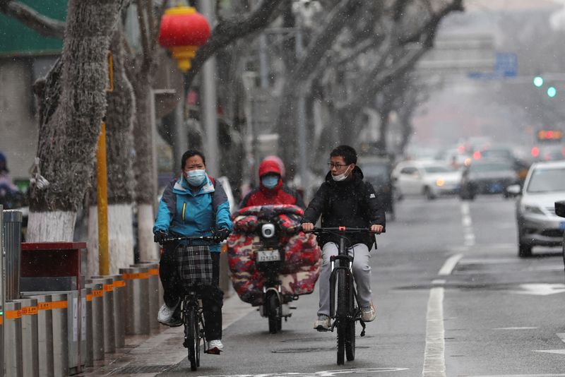 &copy; Reuters. People ride bikes on a street amid snowfall, following the coronavirus disease (COVID-19) outbreak, in Beijing, China March 17, 2022. REUTERS/Tingshu Wang