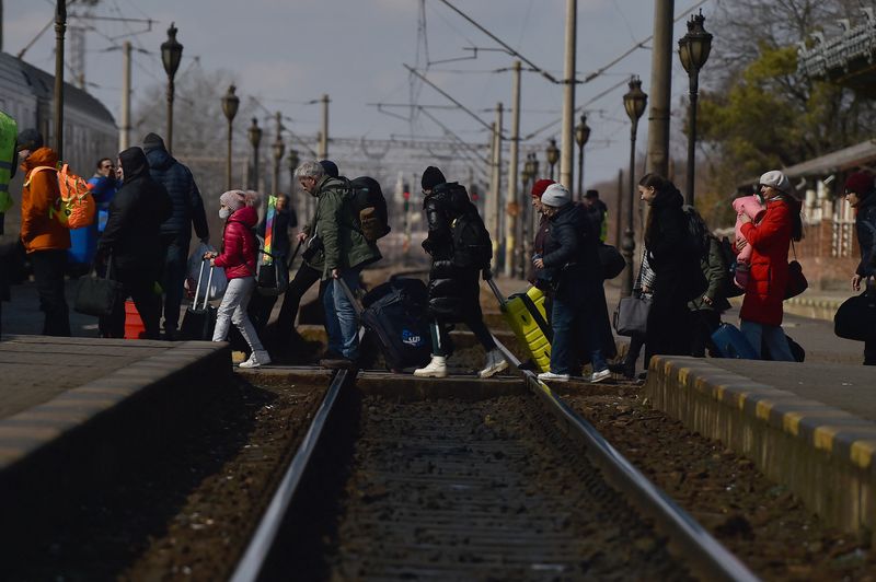 &copy; Reuters. FOTO DE ARCHIVO: Refugiados caminan a través de las vías del tren para subir a un tren a Bucarest en la estación de tren de Suceava después de huir de Ucrania, en  Rumanía, el 17 de marzo 2022. REUTERS/Clodagh Kilcoyne
