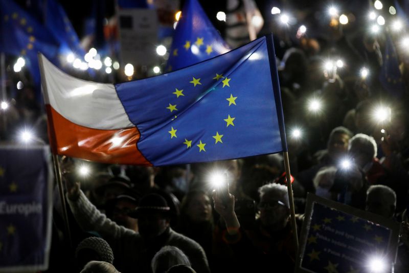 &copy; Reuters. FILE PHOTO: People hold flags and light up their mobile phones during a rally in support of Poland's membership in the European Union after the country's Constitutional Tribunal ruled on the primacy of the constitution over EU law, undermining a key tenet