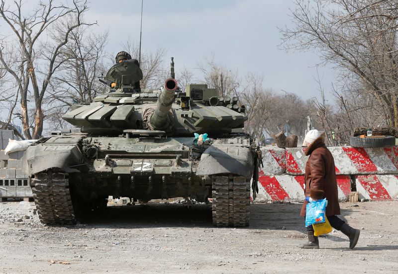 © Reuters. A local resident walks past a tank of pro-Russian troops during Ukraine-Russia conflict in the besieged southern port city of Mariupol, Ukraine March 18, 2022. REUTERS/Alexander Ermochenko