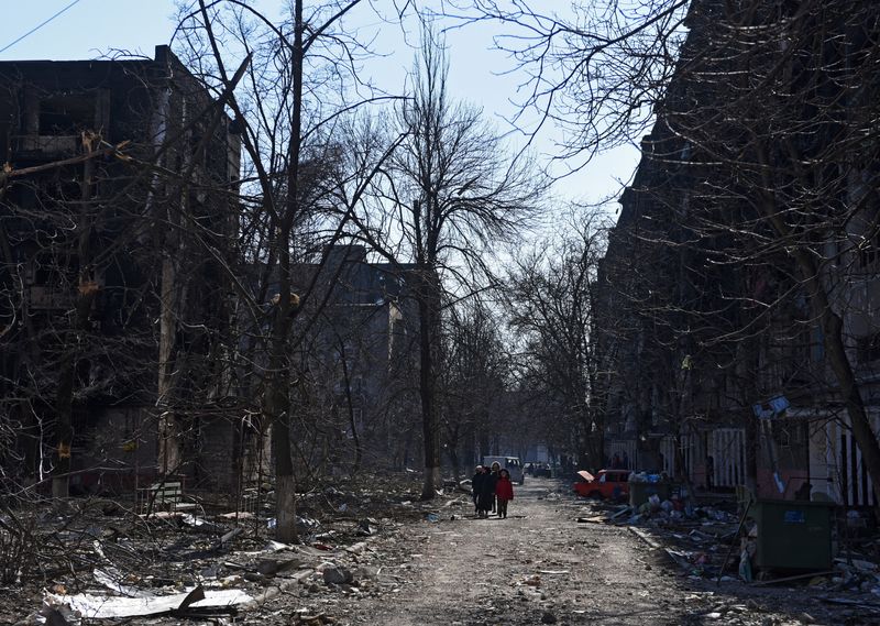 © Reuters. سكان محليون يسيرون قرب مباني سكنية في ماريبول يوم الجمعة دمرت خلال الصراع بين أوكرانيا وروسيا. تصوير:رويترز.
