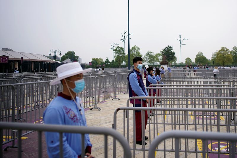 &copy; Reuters. FILE PHOTO: Staff members wearing face masks stand outside the Shanghai Disneyland theme park as it reopens following a shutdown due to the coronavirus disease (COVID-19) outbreak, at Shanghai Disney Resort in Shanghai, China May 11, 2020. REUTERS/Aly Son