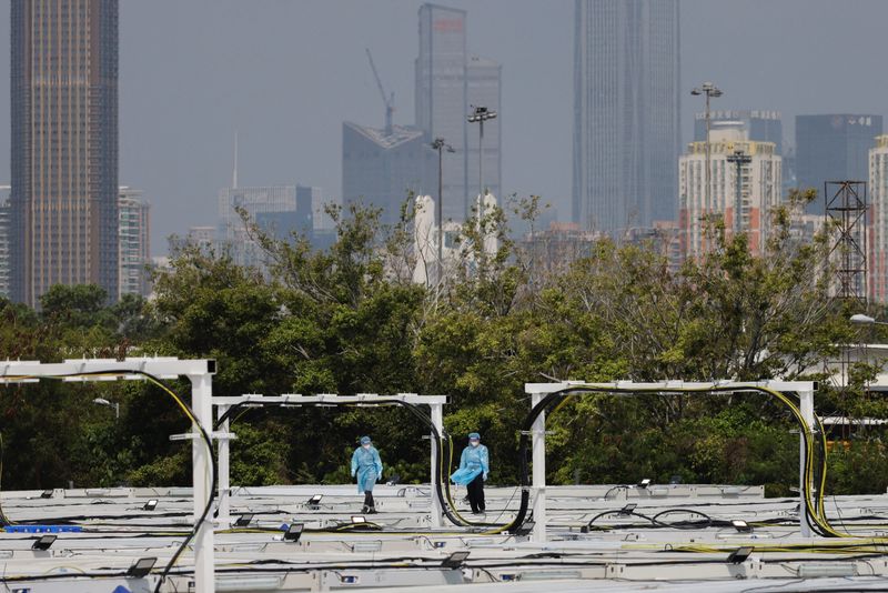 &copy; Reuters. Workers wearing personal protective equipment (PPE) walk on the rooftop of a coronavirus disease (COVID-19) isolation facility, amid the pandemic, in Hong Kong, China March 21, 2022. REUTERS/Tyrone Siu