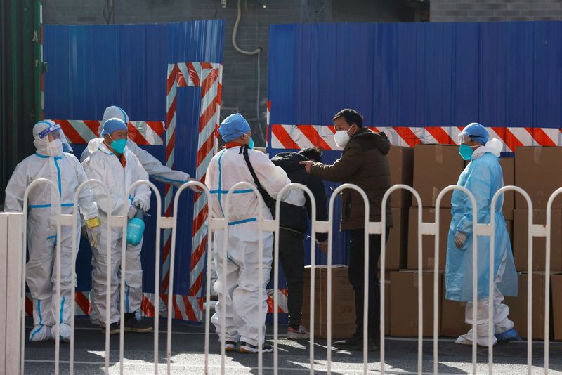 &copy; Reuters. Workers in protective suits stand near boxes outside a sealed off area following the coronavirus disease (COVID-19) outbreak in Beijing, China March 21, 2022. REUTERS/Carlos Garcia Rawlins