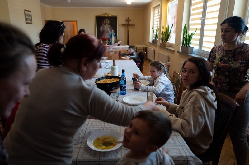 &copy; Reuters. Un grupo de refugiados por la invasión rusa de Ucrania come en un edificio de la Iglesia católica en Lubaczow, Polonia, el 21 de marzo de 2022. REUTERS/Kacper Pempel