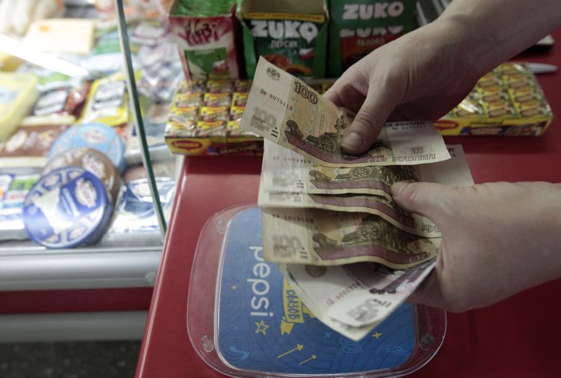 &copy; Reuters. FILE PHOTO: A shop assistant demonstrates Russian rouble banknotes at a grocery in Stavropol, southern Russia, January 21, 2016. Russia's rouble fell further on January 20, setting a new record low of over 81 roubles per dollar as a bearish mood gripped R