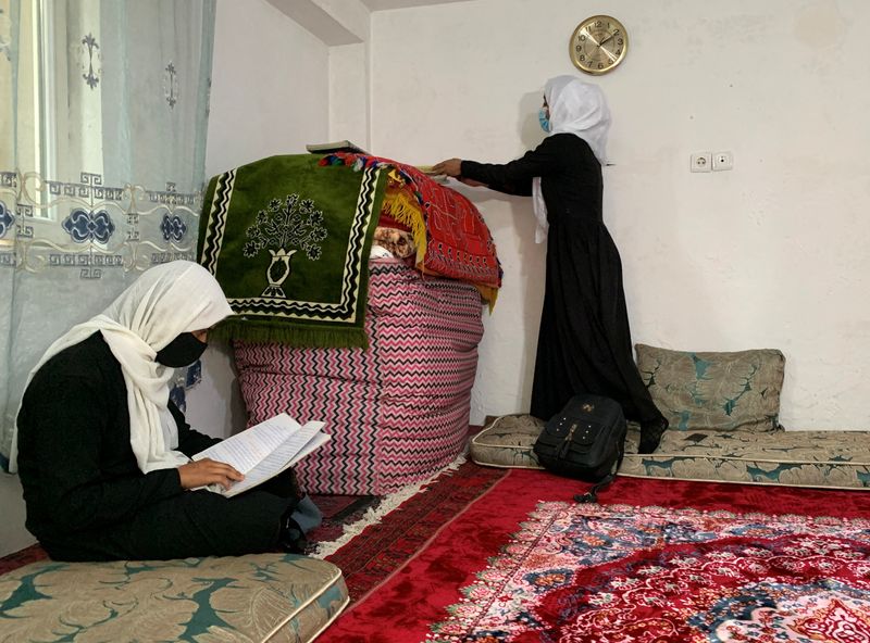 &copy; Reuters. طالبة أفغانية تراجع دروسها فيما تقوم أخرى بإفراغ محتويات حقيبتها المدرسية داخل منزل في العاصمة الأفغانية كابول يوم الأربعاء. تصوير: رويترز.