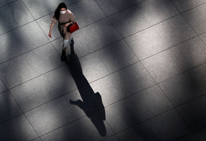 &copy; Reuters. FILE PHOTO: A woman wearing a protective face mask walks inside a buildng at a business district, amid the coronavirus disease (COVID-19) outbreak, in Tokyo, Japan November 18, 2020.  REUTERS/Issei Kato