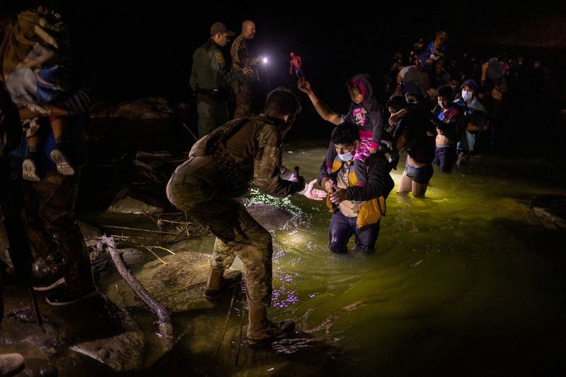 &copy; Reuters. FOTO DE ARCHIVO-Agentes de la patrulla fronteriza y miembros de la Guardia Nacional del Ejército de Texas iluminan el camino mientras migrantes en busca de asilo procedentes de América Central y del Sur vadean el río Bravo hacia Estados Unidos desde M