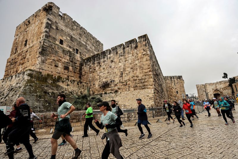&copy; Reuters. متسابقون يشاركون في ماراثون القدس يعبرون باب يافا في البلدة القديمة بمدينة القدس يوم الجمعة. تصوير: عمار عوض - رويترز.