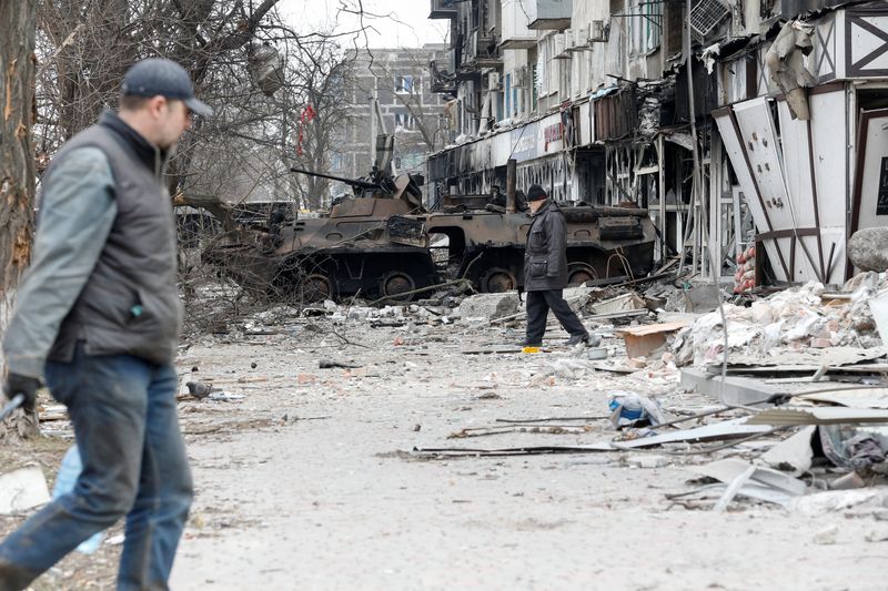 &copy; Reuters. سكان محليون وسط آليات عسكرية مدمرة وآثار قصف في ماريوبول يوم 25 مارس آذار 2022. تصوير: ألكسندر إيرموشينكو - رويترز