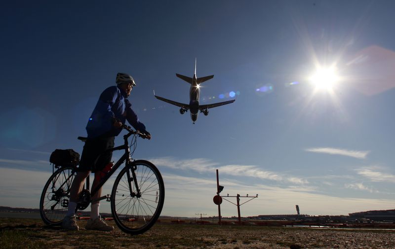 © Reuters. FILE PHOTO: A cyclist out enjoying unseasonably warm temperatures watches a plane land at Ronald Reagan Washington National Airport January 31, 2012.  Temperatures in the nation's capital reached the mid 60's today.  REUTERS/Kevin Lamarque  