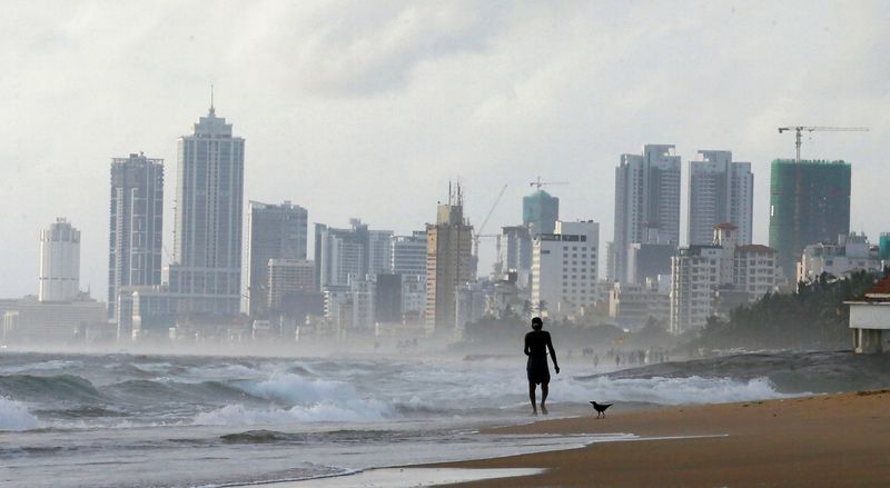 &copy; Reuters. FILE PHOTO: A man walks along a beach, against the backdrop of Colombo's Financial City, Sri Lanka June 12, 2018. REUTERS/ Dinuka Liyanawatte