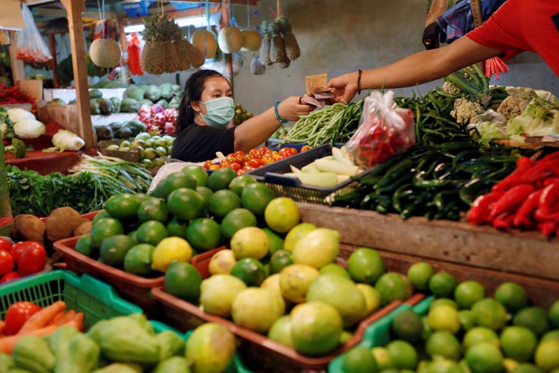 &copy; Reuters. A woman wearing a face mask passes banknotes as she shops for vegetables at a traditional market amid the spread of coronavirus disease (COVID-19) in Jakarta, Indonesia March 18, 2020. REUTERS/Willy Kurniawan