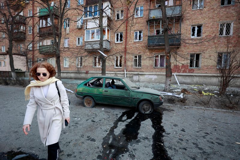 &copy; Reuters. امرأة تسير بالقرب من سيارة ومبنى تعرضوا للضرر في غارة عسكرية وسط غزو روسيا لأوكرانيا في كييف يوم 23 مارس آذار 2022 - رويترز